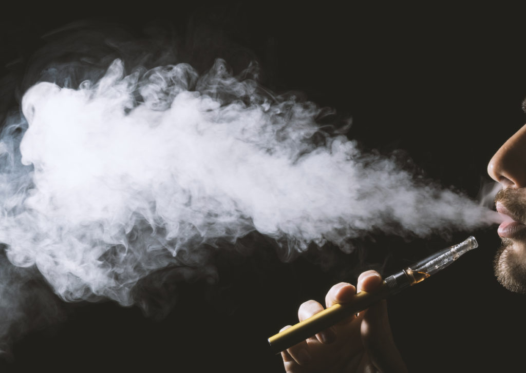 Young man holding and vaping an electronic cigarette, e-cig, ecigarette.